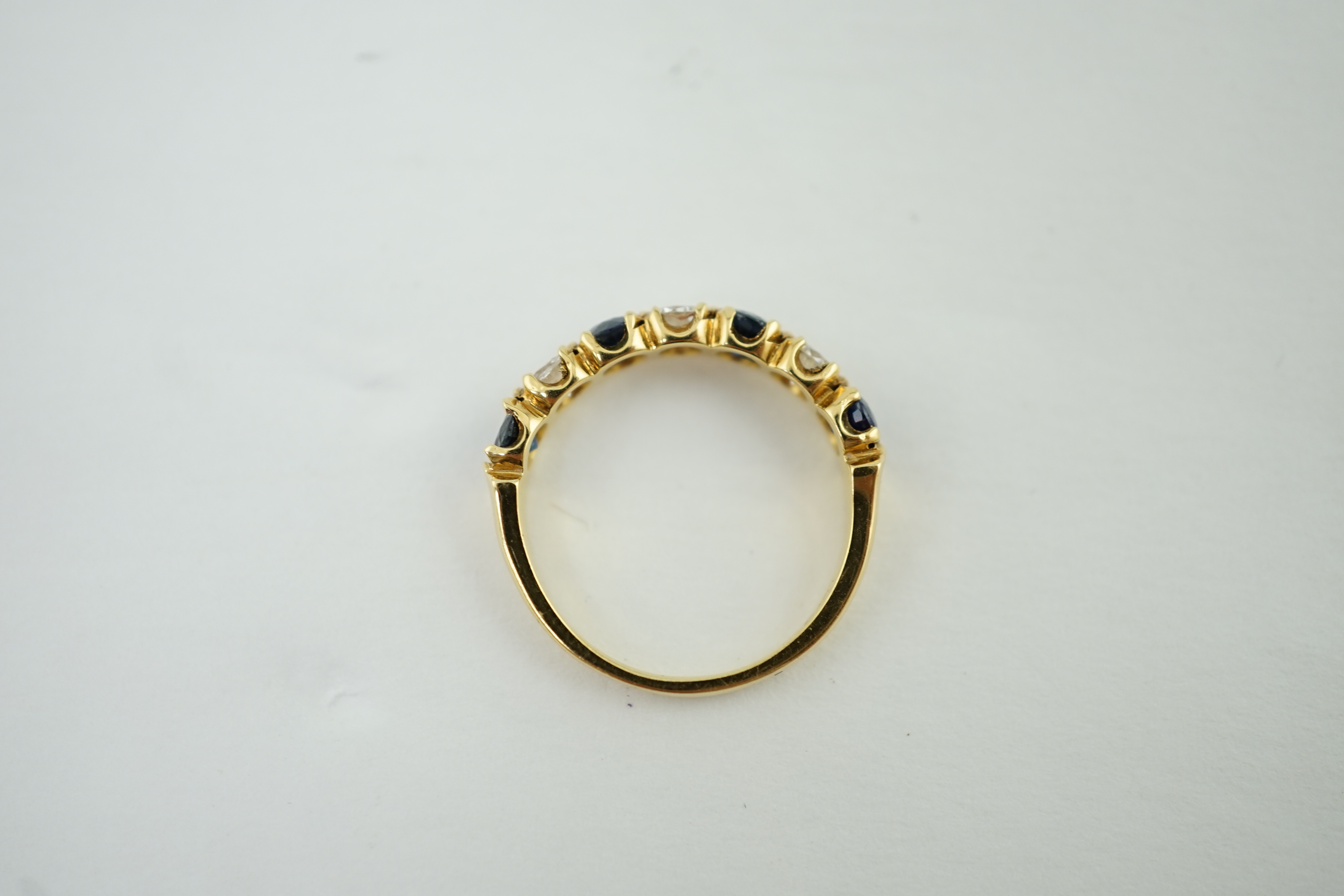 A modern 18ct gold, four stone sapphire and three stone diamond set half hoop ring